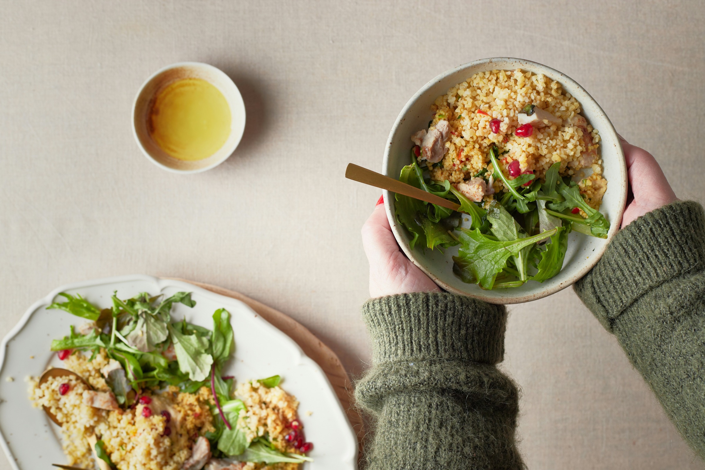 A grain bowl with leafy greens held above a table