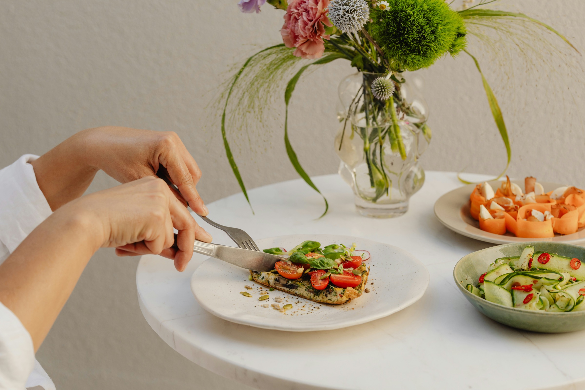 Person eating a relaxed dinner at a table while tracking meal and symptom patterns