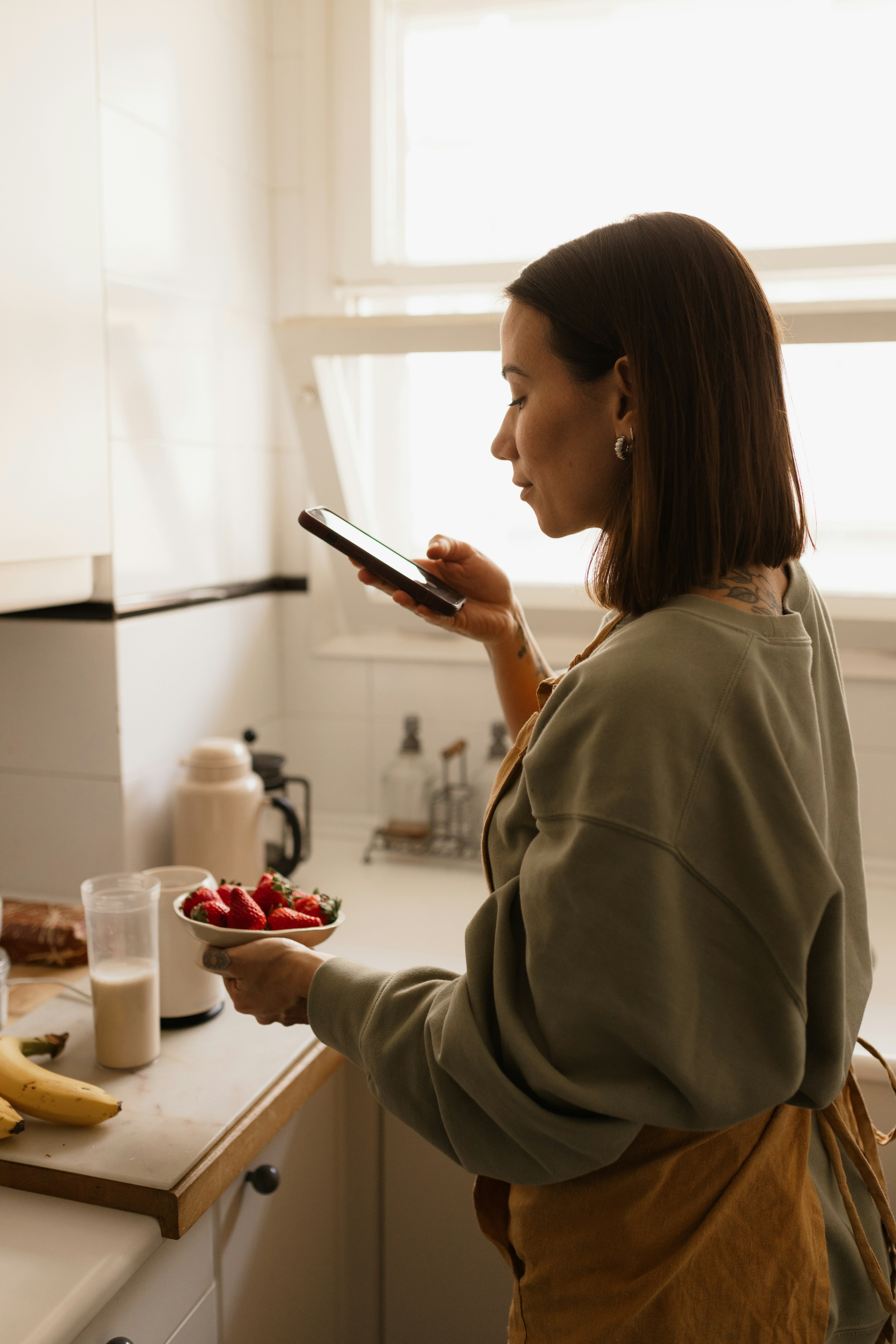 Person checking a phone while preparing breakfast