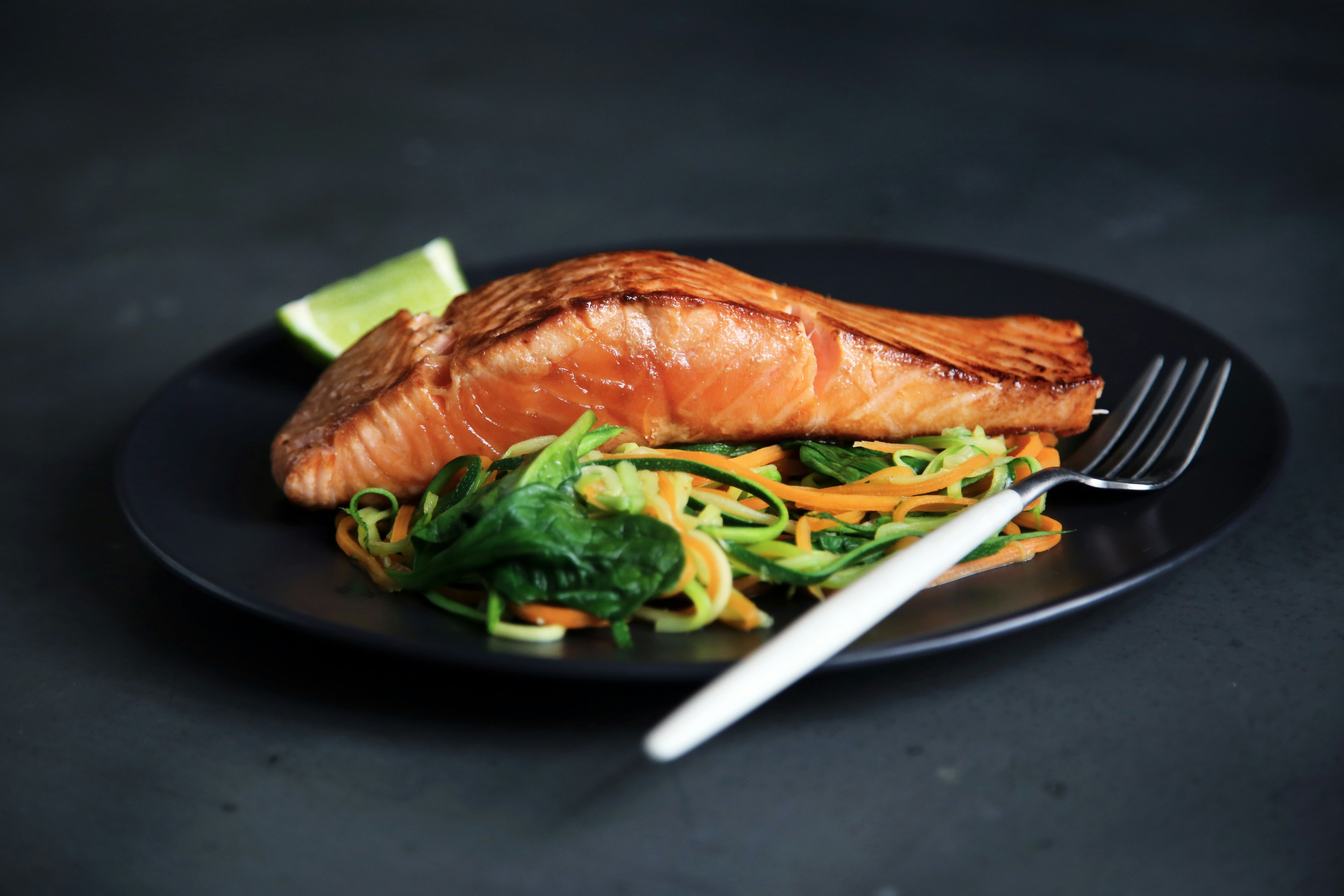 Cooked salmon with vegetables on a dark plate